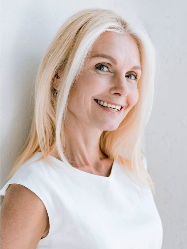 Smiling woman with blonde hair, white clothing.