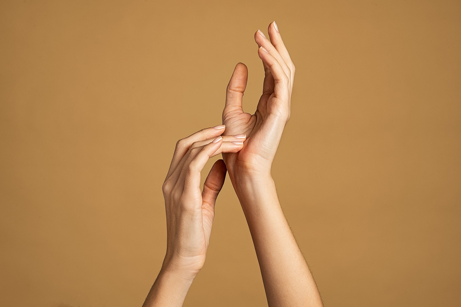 Elegant hands against a warm brown background.