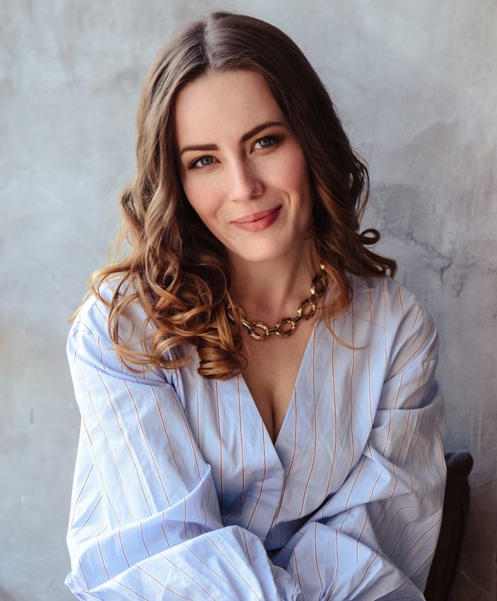 Smiling woman in blue striped blouse with necklace.