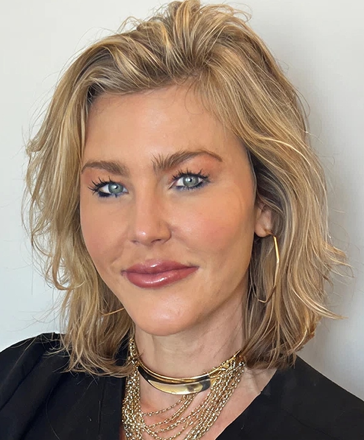 Woman wearing sunglasses, smiling outdoors.