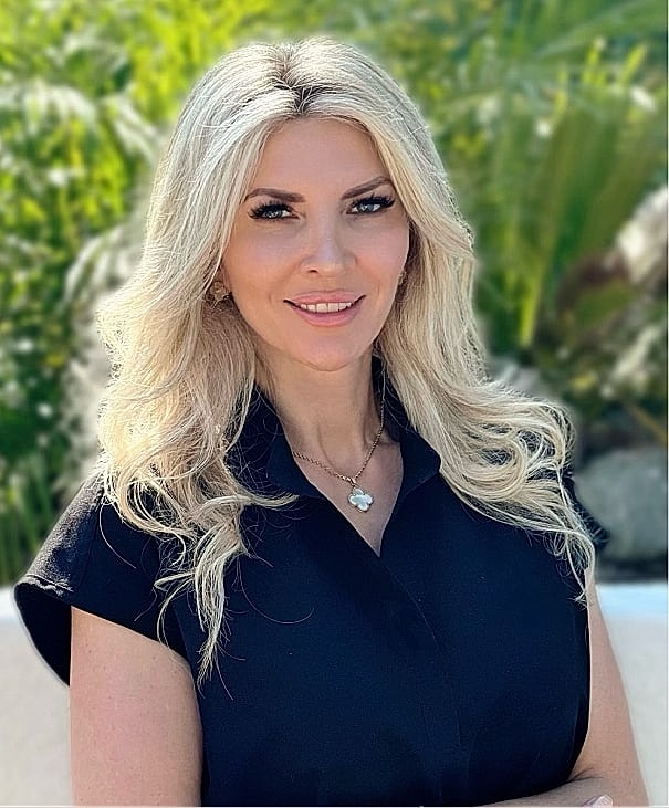 Smiling woman in a black outfit outdoors.