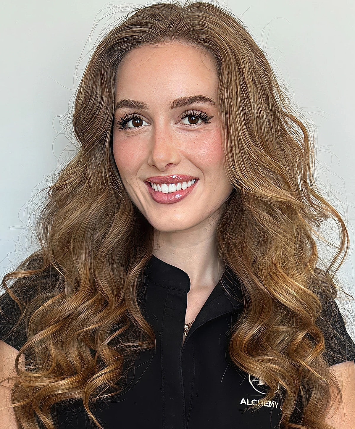 Smiling woman with wavy hair and black outfit.
