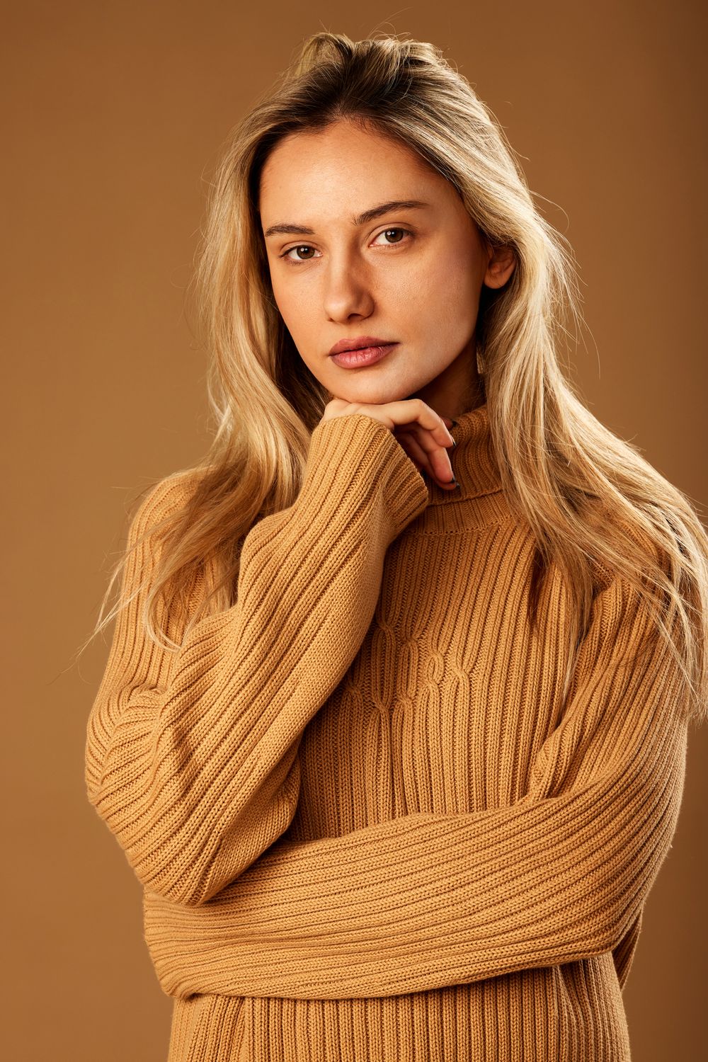 Woman in cozy sweater against plain background.